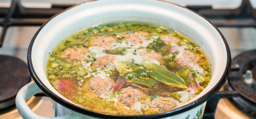 Homemade soup with meatballs in a saucepan. Closeup.