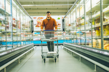 man walk with cart between rows with refrigerators.