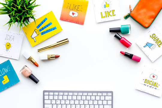 Beauty blogger workplace concept. Keyboard, cosmetics, social media icons on white desk top view space for text