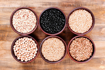 Healthy various cereals in the bowls on the wooden table