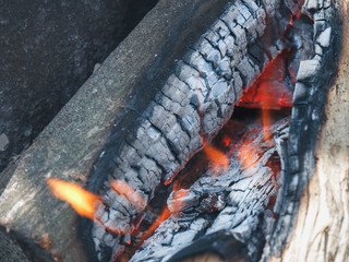 The wooden logs burn in the bonfire before cooking a food on a picnic.