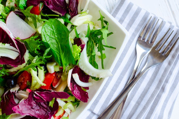 Fresh summer green salad mix on a wooden table