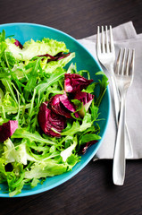 Fresh summer green salad mix on a wooden table