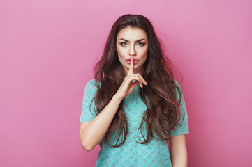 Shh! Portrait of pretty female with stylish hairdo keeps fingers on lips, demonstrates silence...