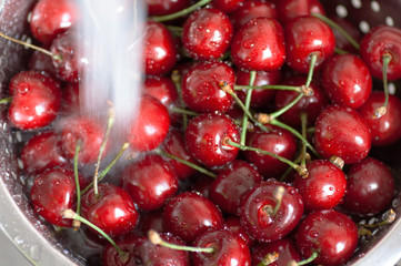 cherry berries in a colander under running water