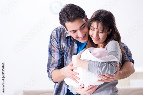 Young parents with their newborn baby near bed cot Young parents with their newborn baby near bed cot