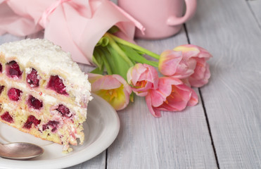 A cake with cherries and pink tulips on white wooden table