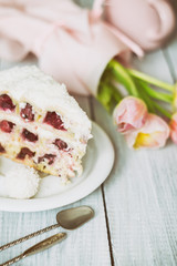 A cake with cherries and pink tulips on white wooden table