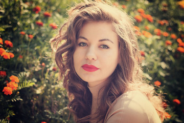 woman poses on background bed of flowers