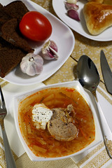 Russian soup with meat, dressed with sour cream, with bread, garlic, pies and tomato. Set for lunch, dinner set. Homemade comfort food for a cold day