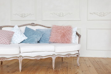 white vintage sofa with blue and pink pillows near the white wall in the spring decorated room