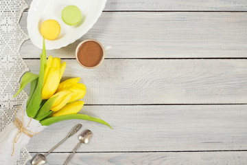 Yellow tulips, chocolate and macarons on white wooden table