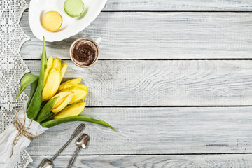 Yellow tulips, chocolate and macarons on white wooden table