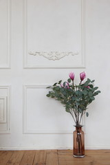 blossom  pink flowers of rhe magnolia and eucalyptus leaves near the white wall in rhe sping decorated room. hello March April  May