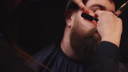 woman barber shaves customer with a dangerous razor in a barber, close-up