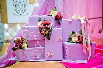 Purple gift boxes with white and red flowers . Stack of violet gift boxes