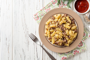 Fusilli pasta with minced meat and onion in navy-style on white wooden table. Makarony po-flotski, Russian dish.
