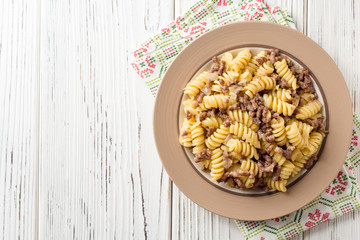 Fusilli pasta with minced meat and onion in navy-style on white wooden table. Makarony po-flotski, Russian dish.