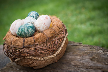 Basket with natural colored Easter eggs over green grass background