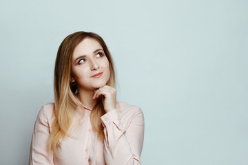 Body language and emotions. serious woman  blonde in a pink blouse on a white background.  girl looks aside with pensive expression
