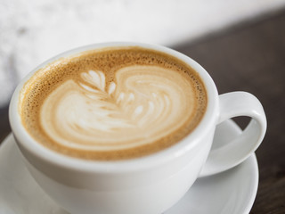 Cup of cappuccino on wooden table with white brick wall background.