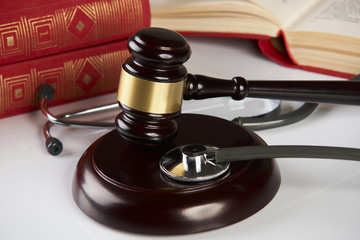 Judges gavel  with law books and medical stethoscope on white table in a courtroom or enforcement office, close-up. selective focus. Medicine law concept