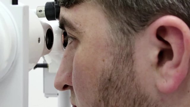Patient in ophthalmology clinic. Man looks in synoptophore - ophthalmic instrument, used for diagnosing imbalance of eye muscles and treating them by orthoptic methods, for treatment of strabismus
