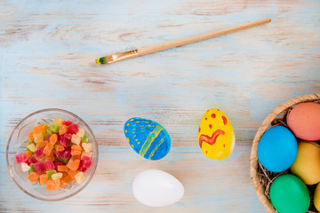 Easter concept a colored eggs next to candied fruits and brush on a wooden bacground