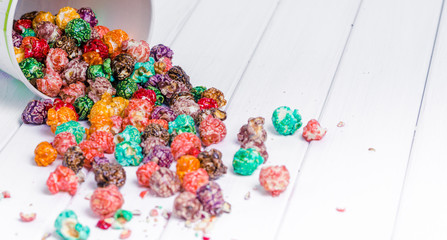 Brightly Colored Candied Popcorn, white background. Horizontal image of Junk food, fruit flavored popcorn in light pink bowl. Colorful, rainbow, candy coated popcorn. Shallow focus on popcorn in bowl.