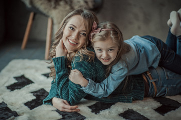 Smiling mother with her daughter in the room on the carpet