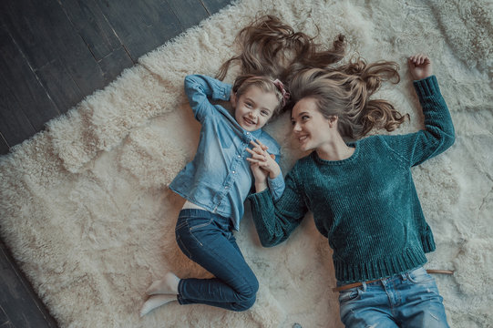 Smiling mother with her daughter in the room on the carpet