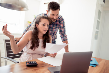 Couple at home paying bills with laptop