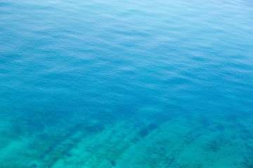 The texture of the water. Clear blue sea water with a stone slab on the bottom.
