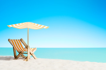 A chaise longue under an umbrella on the sandy beach by the sea and sky with copy space