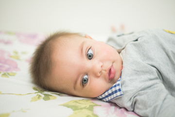 Blue-eyed baby boy lying on the bed