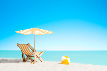 Lounge chair with parasol and beach ball on the coast