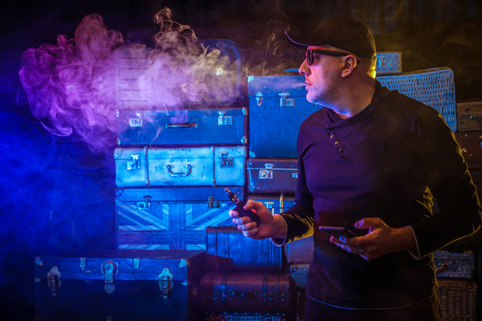 A man is launching steam. Man with an electronic cigarette. Steam clubs around the smoker. Vape