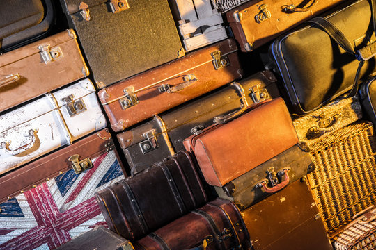 Wall of old suitcases. Many suitcases. Retro bags. Travel bags dumped in one heap.