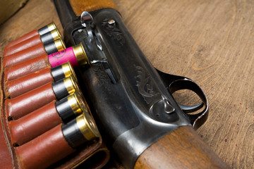 Hunting rifle and ammunition lie on wooden background.