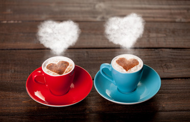 Two color cups of coffee with heart shape steams