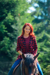 Fototapeta na wymiar Redehad girl with horse in the forest