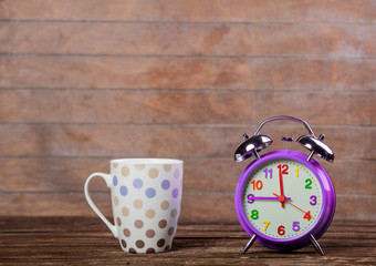 Cup of coffee or tea with metal alarm clock