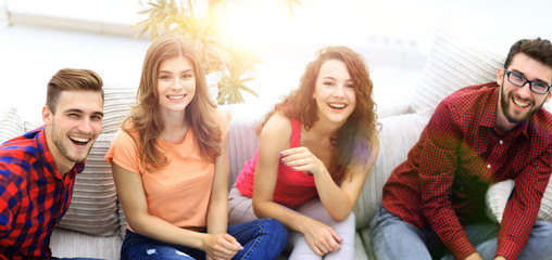Obraz premium group of cheerful friends watching videos, sitting on the couch