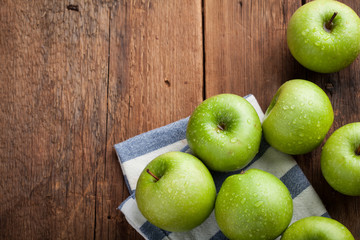 Ripe green apples in a wooden bowl on an old rustic table. Useful fruits on wooden background. Top view with copy space