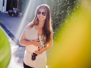 happy and optimistic digital nomad girl standing outside at the pool during workation