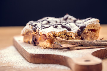 Freshly baked apple pie sprinkled with powdered sugar and topped with chocolate. Delicious homemade pastries with shallow depth of field.