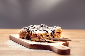 Freshly baked apple pie sprinkled with powdered sugar and topped with chocolate. Delicious homemade pastries with shallow depth of field.