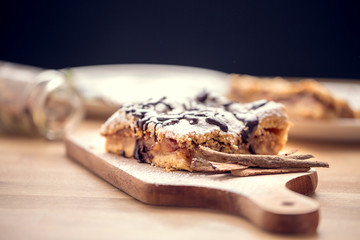 Freshly baked apple pie sprinkled with powdered sugar and topped with chocolate. Delicious homemade pastries with shallow depth of field.