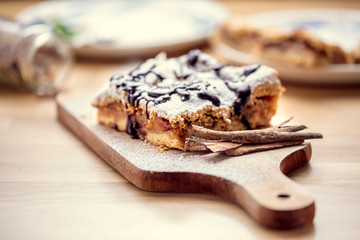 Fototapeta na wymiar Freshly baked apple pie sprinkled with powdered sugar and topped with chocolate. Delicious homemade pastries with shallow depth of field.
