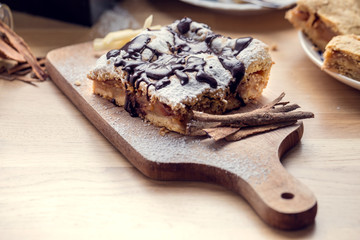 Freshly baked apple pie sprinkled with powdered sugar and topped with chocolate. Delicious homemade pastries with shallow depth of field.